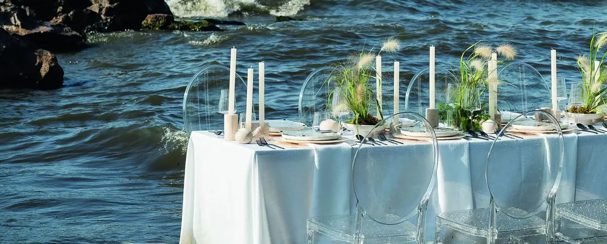 A long table set at the water’s edge.